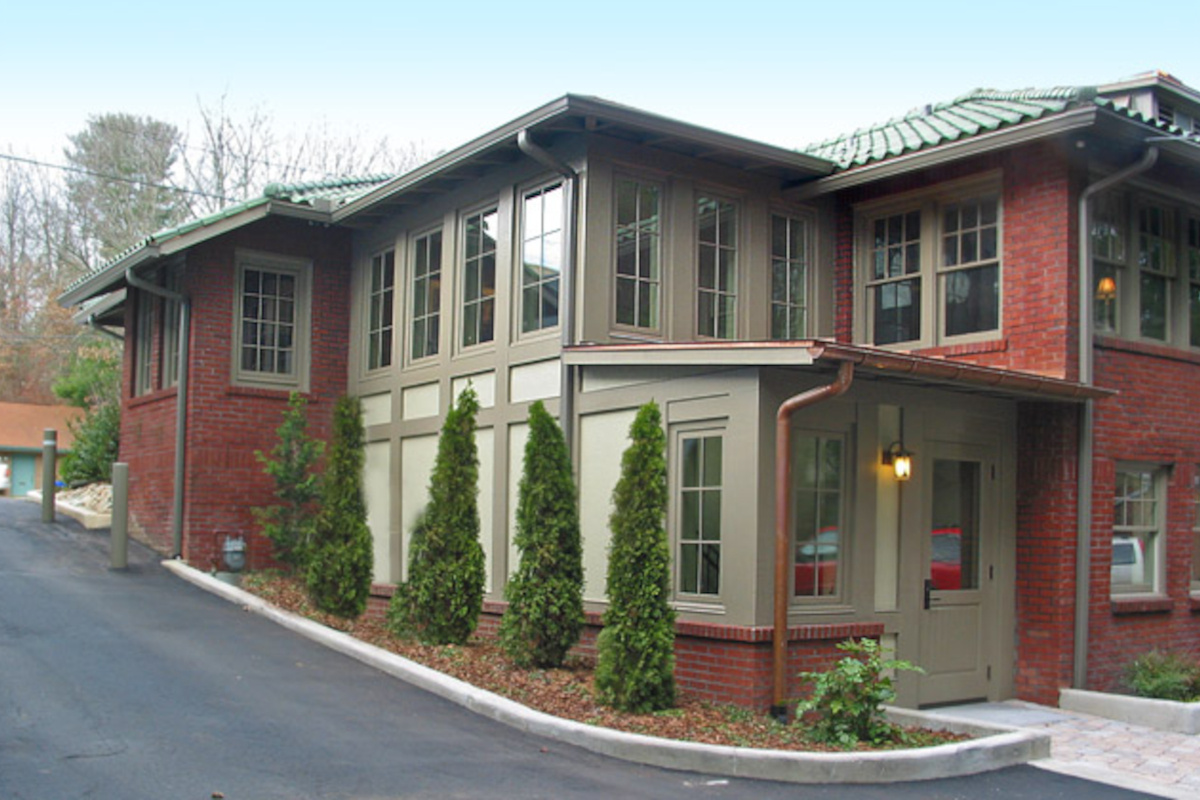 Image of craftsman style brick and wooden office building with green clay roof