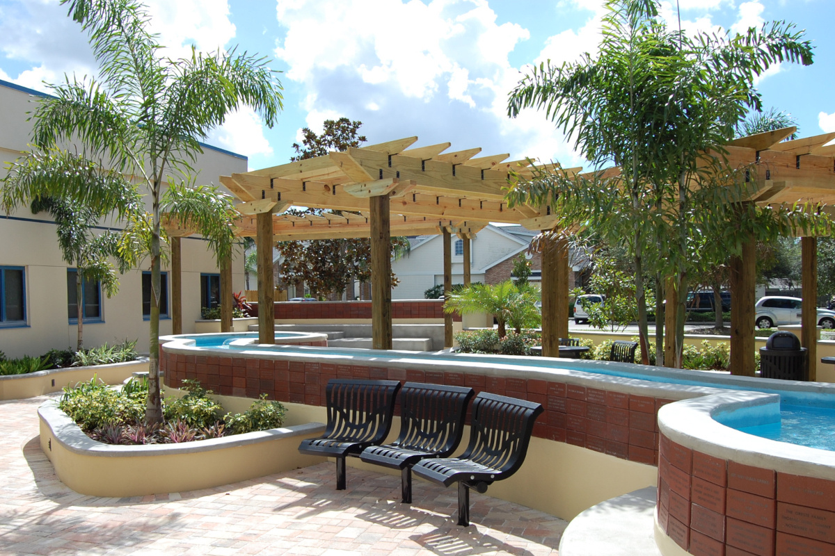 Image of public library reading garden with fountains, donor names on red brick walls, wooden pergolas and steel seating