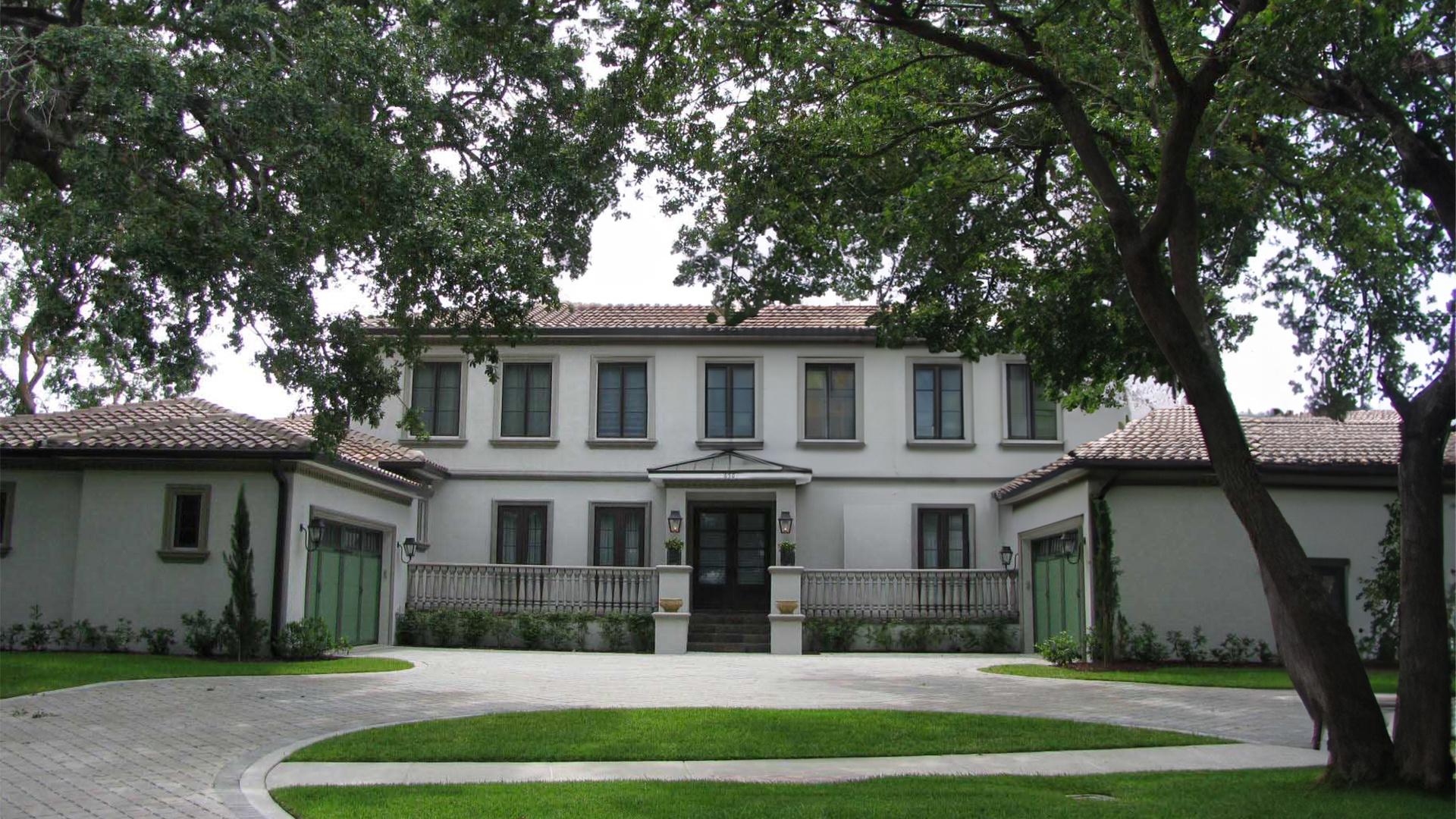 Image of beautiful white modern italianate home with dark bronze trim, red tile roof, and green garage doors