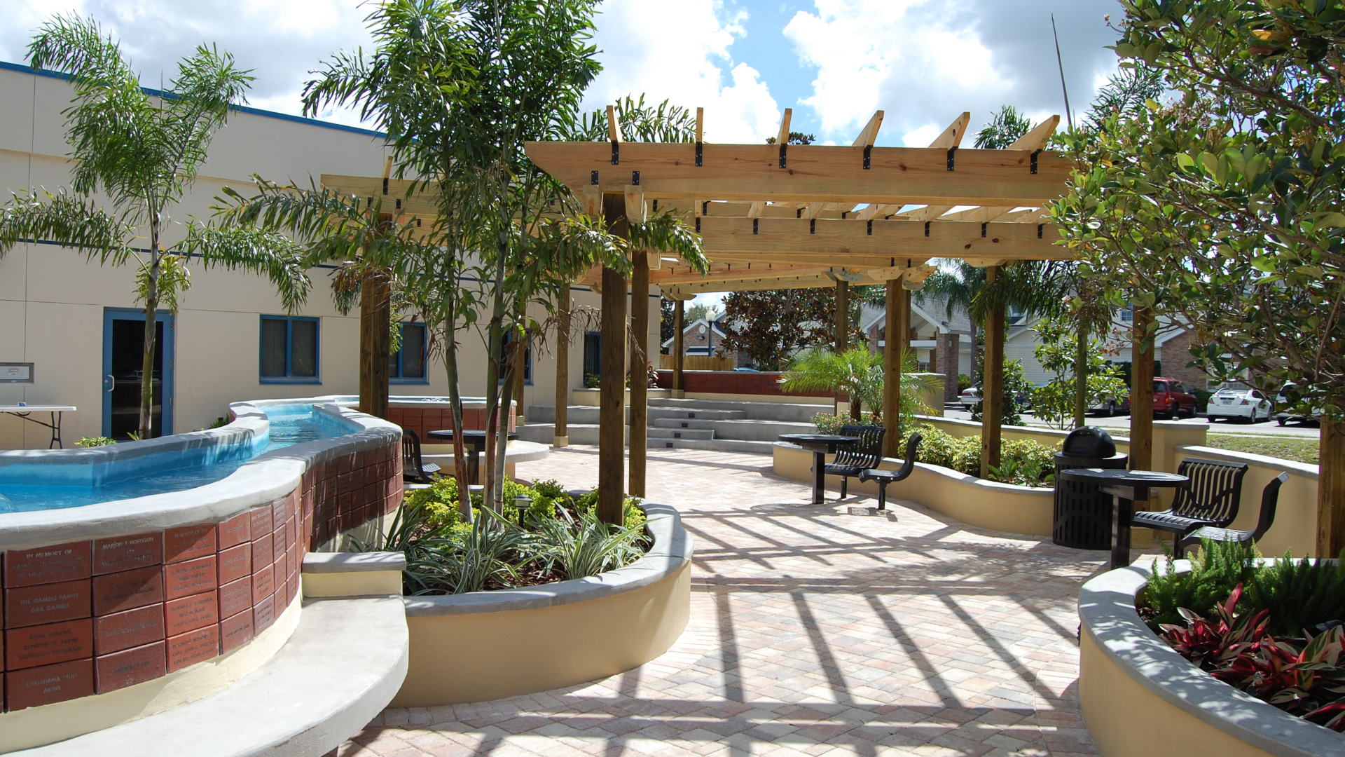 Image of public library reading garden with fountains, donor names on red brick walls, wooden pergolas and steel seating