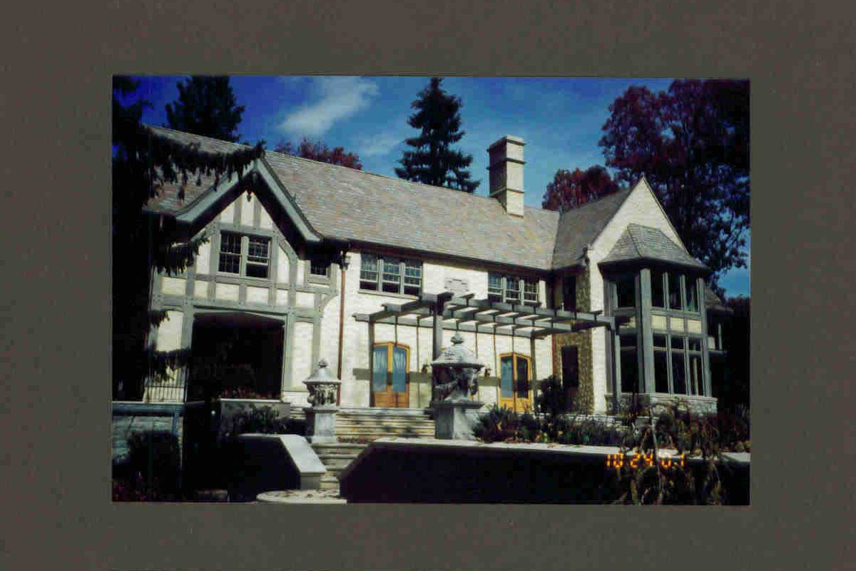 Image of historic Tudor style home with white exterior walls and grey trim with large wooden glass inlay doors