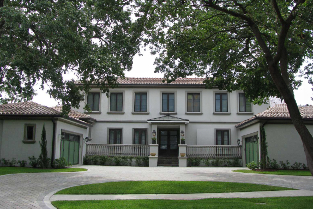 Image of white Italianate home with red clay roof and green garage doors